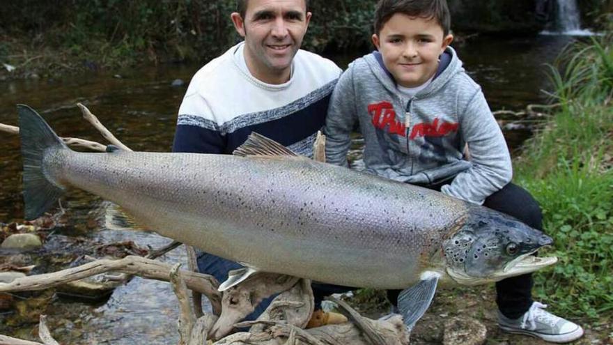 Quique Berrocal, con su hijo Javi, posa con un salmón disecado, pescado hace más de una década por Lalín el del Requejo, que pesó 15,100 kilos y que se muestra en el Proyecto Arca de Pravia.