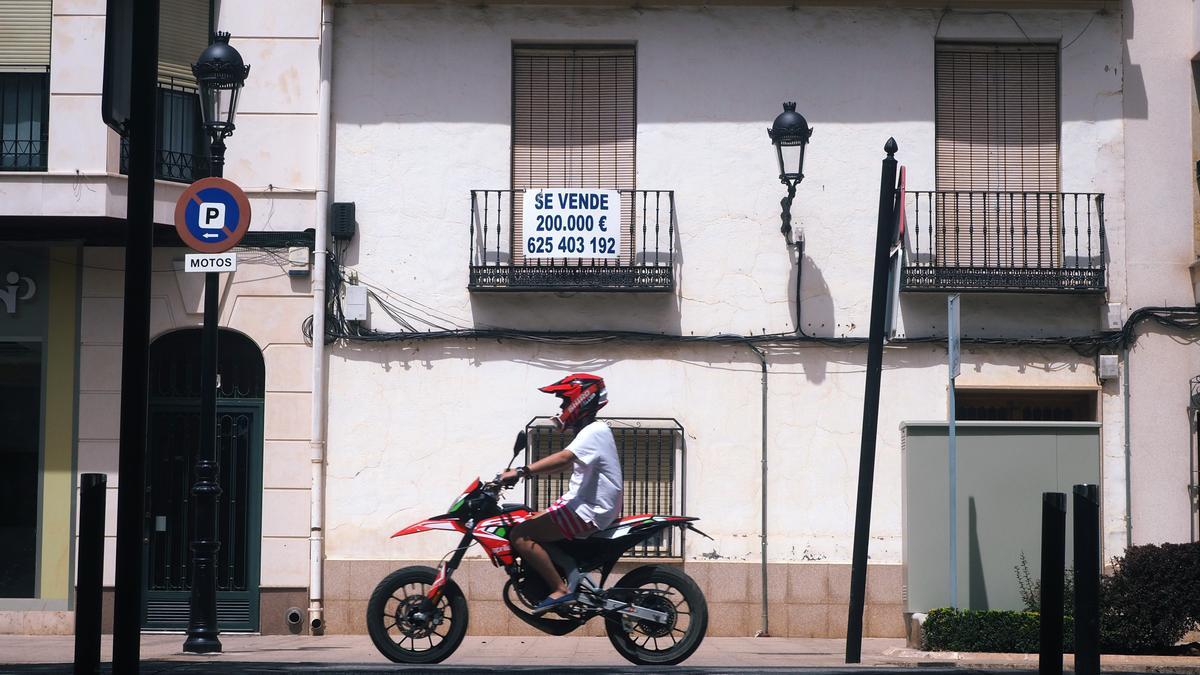 Un joven pasa delante de una casa en venta en Tomelloso, Ciudad Real