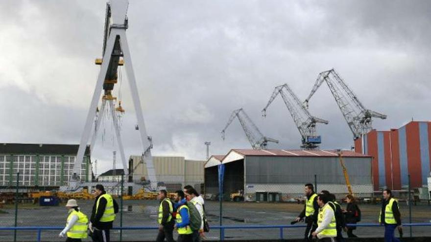 Empleados del naval de la comarca de Ferrol con las instalaciones de Navantia al fondo. / kiko