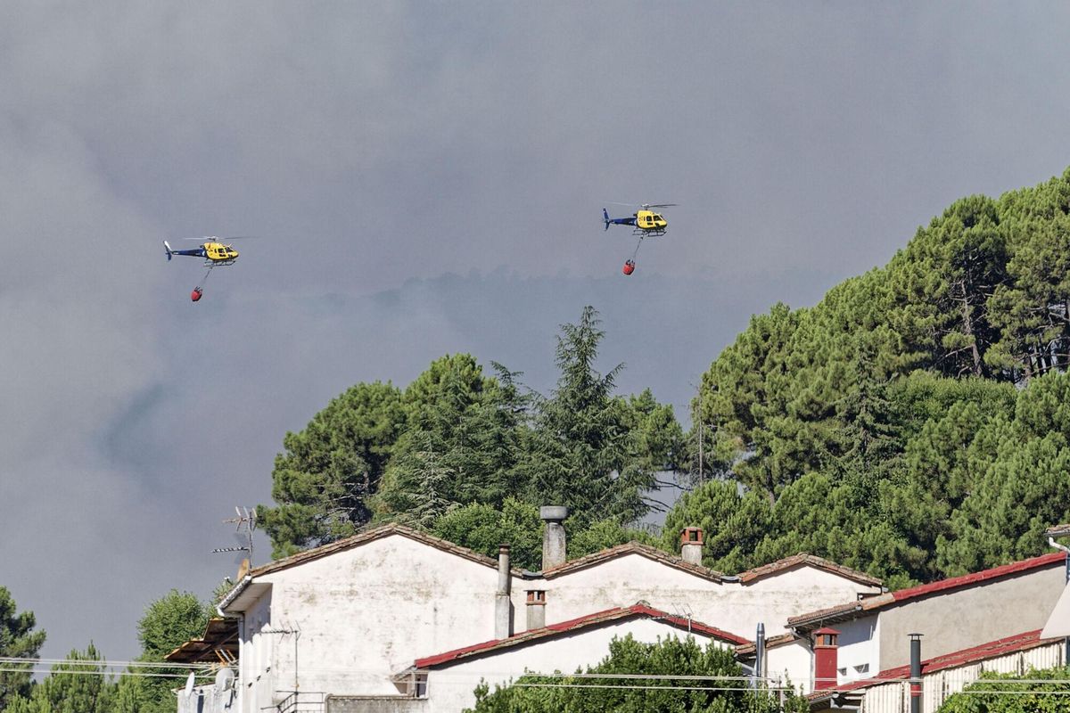 Dos helicópteros de los bomberos trata de controlar el fuego declarado este martes por Mombentrán, Ávila. Un total de 101 militares y 47 medios de la Unidad Militar de Emergencias (UME) se encuentran desplegados actualmente en el Barranco de las Cinco Villas por el incendio que se declaró en la noche del lunes en esta zona del sur de la provincia de Ávila. EFE/ Raúl Sanchidrián. Sust textos
