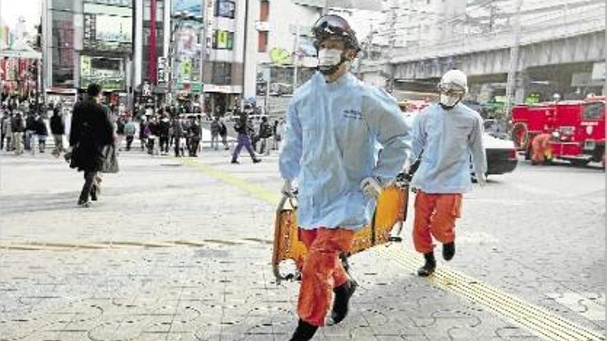 Agents del servei d&#039;emergències en un carrer de Tòquio, més buit del que és habitual en un dissabte.