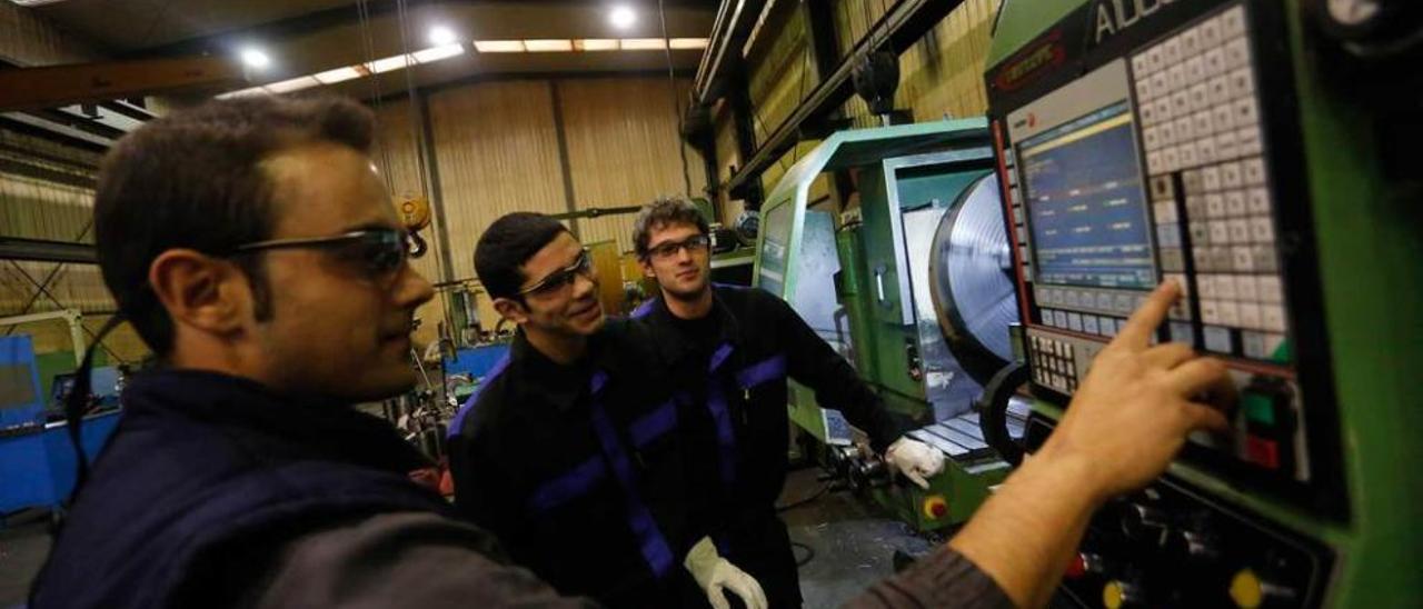 Un trabajador de Asturfeito, en Avilés, con dos aprendices.