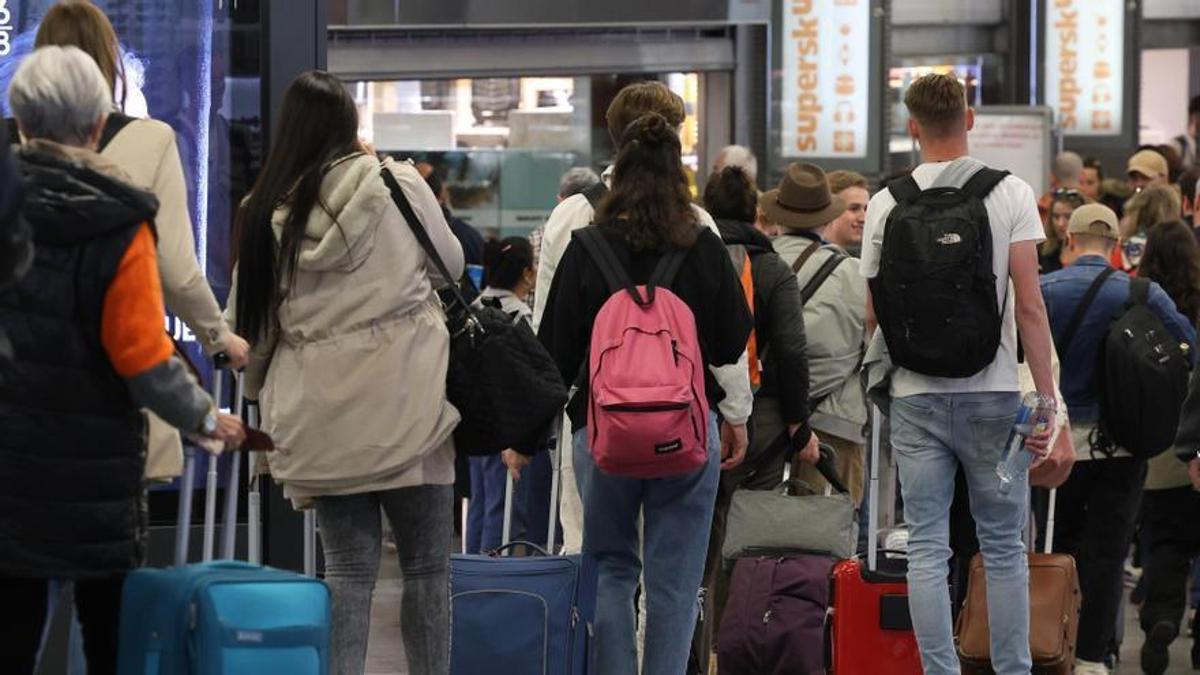 Numerosas personas con maletas salen de viaje en la estación Almudena Grandes-Atocha Cercanías.