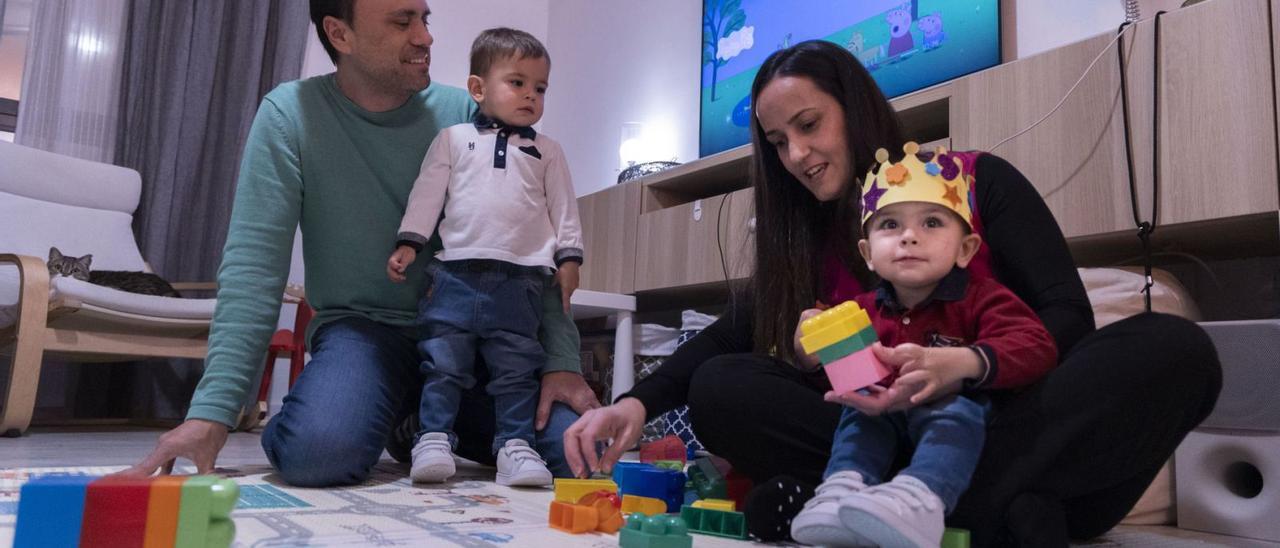 Roberto Ruiz y María del Mar Amer juegan con sus hijos, Xavi y David, en el salón de su casa de Alcàsser. | GERMÁN CABALLERO