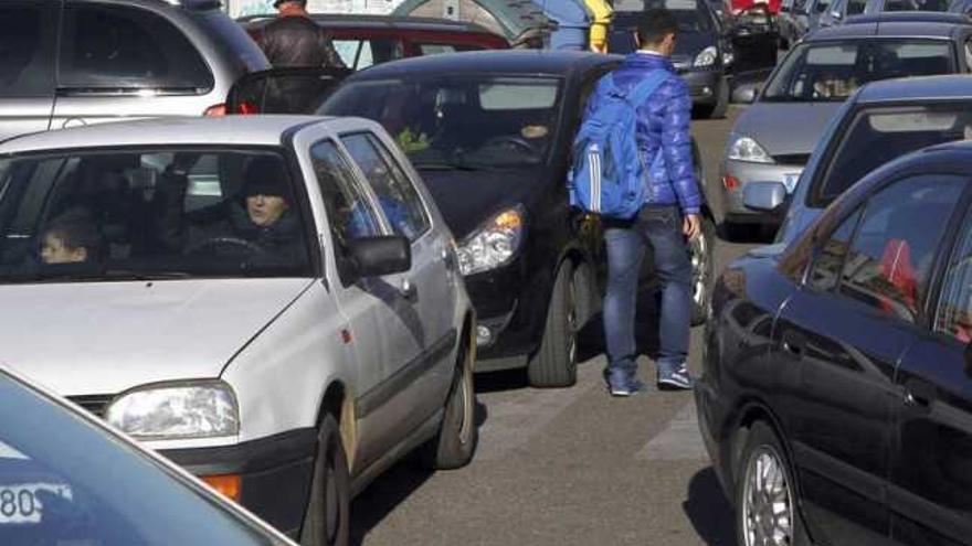 A la izquierda, alumnos a la salida del colegio Gonzalo de Berceo. A la derecha, un estudiante camina entre los numerosos vehículos que se juntan entre el colegio Sancho II y el instituto La Vaguada.