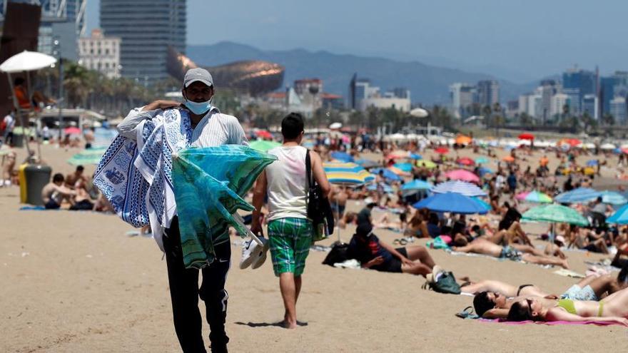 Un venedor ambulant ofereix els seus productes aquest dimecres a la platja de la Barceloneta