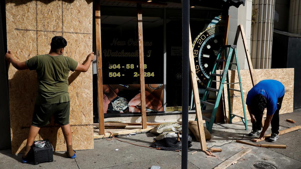 Dos hombres protegen su establecimiento ante la llegada del huracán.