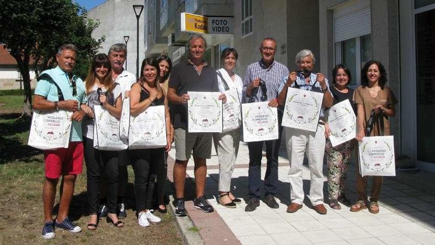 El alcalde de Nigrán, Juan González, posa con comerciantes con las nuevas bolsas de papel. // D.P.