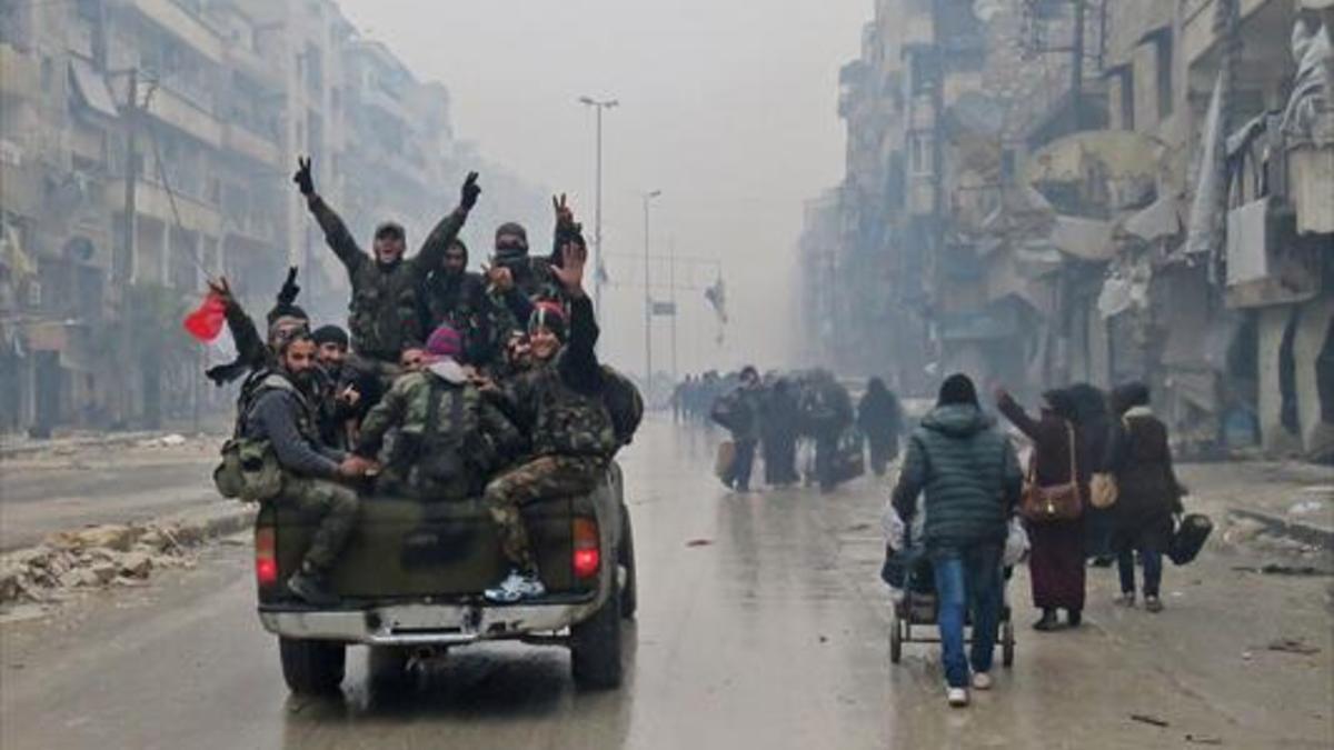Combatientes progubernamentales hacen la señal de la victoria, ayer en una calle de Alepo.