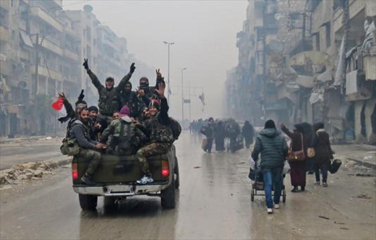 Combatientes progubernamentales hacen la señal de la victoria, ayer en una calle de Alepo.