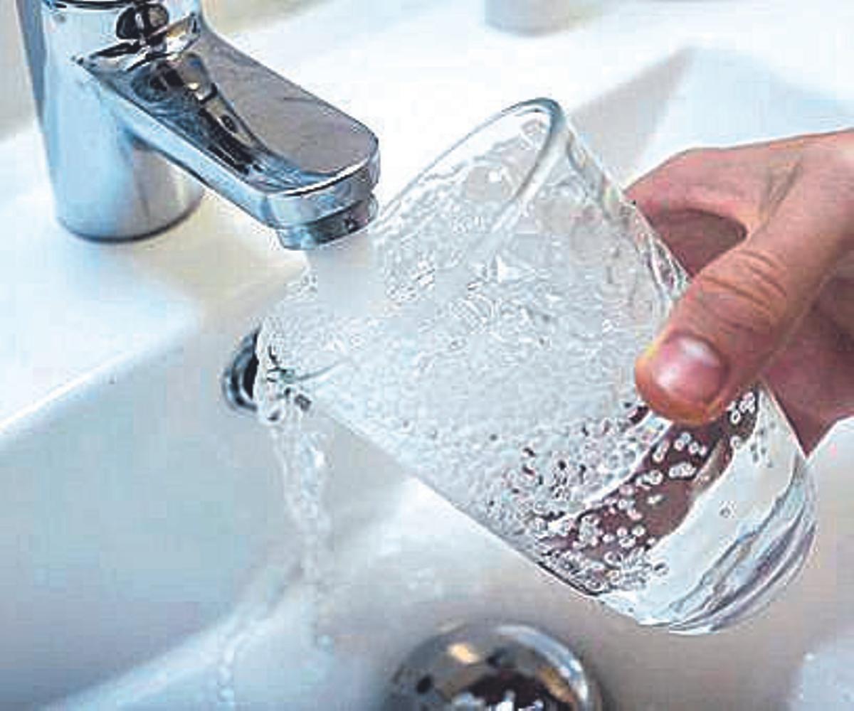 Una persona llena un vaso de agua de un grifo.