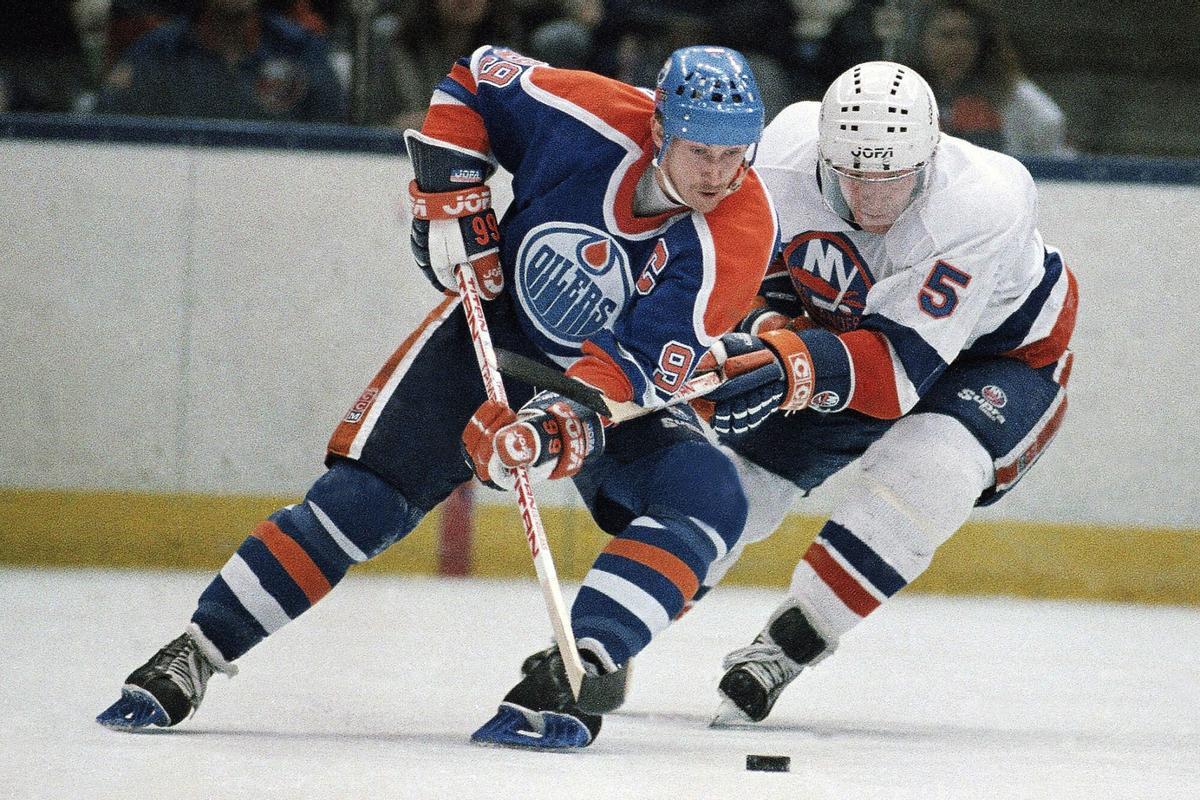FILE - Edmonton Oilers Wayne Gretzky, left, and New York Islanders Denis Potvin (5) jostle for a loose puck during the first period of an NHL hockey game at the Nassau Coliseum in Uniondale, N.Y., March 26, 1988. (AP Photo/Wa Funches). 12185. file photo