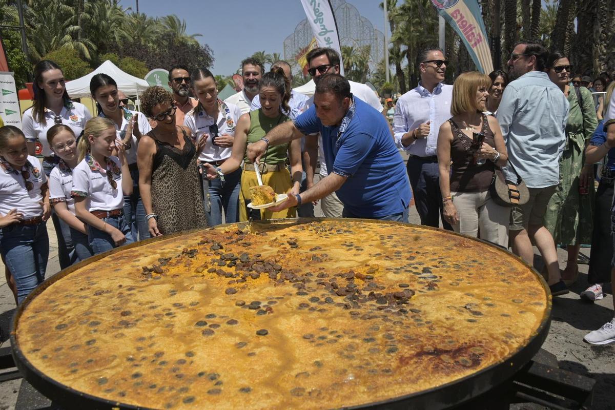 El presidente de la Gestora, Fernando Jaén, entrega un plato de arroz con costra junto a las reinas y damas y la pregonera