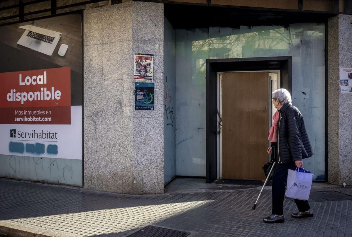 Una mujer pasa, ayer, ante la puerta blindada de la antigua sucursal bancaria de Sant Ferran. | B.RAMON