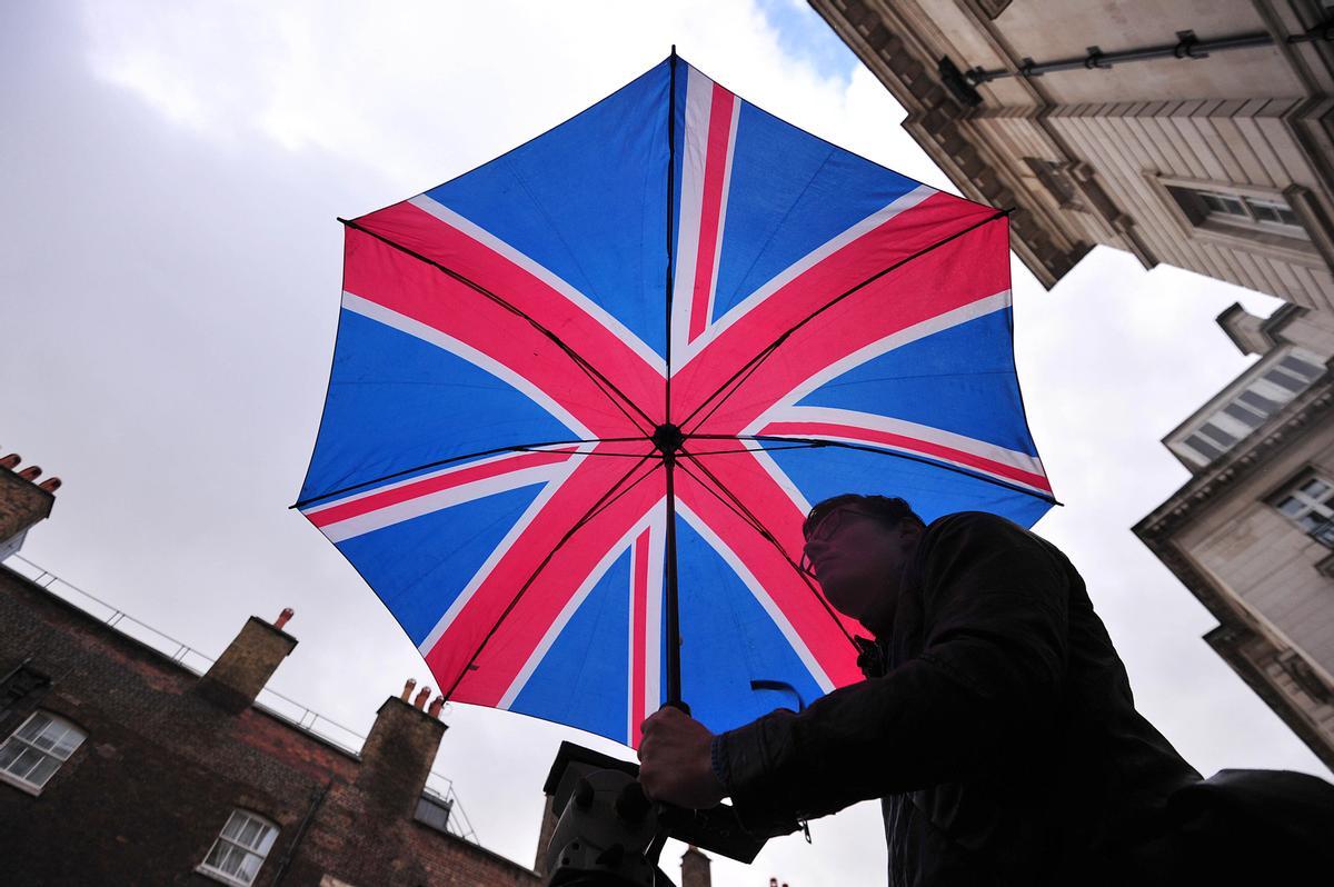 Un hombre bajo un paraguas con la bandera británica