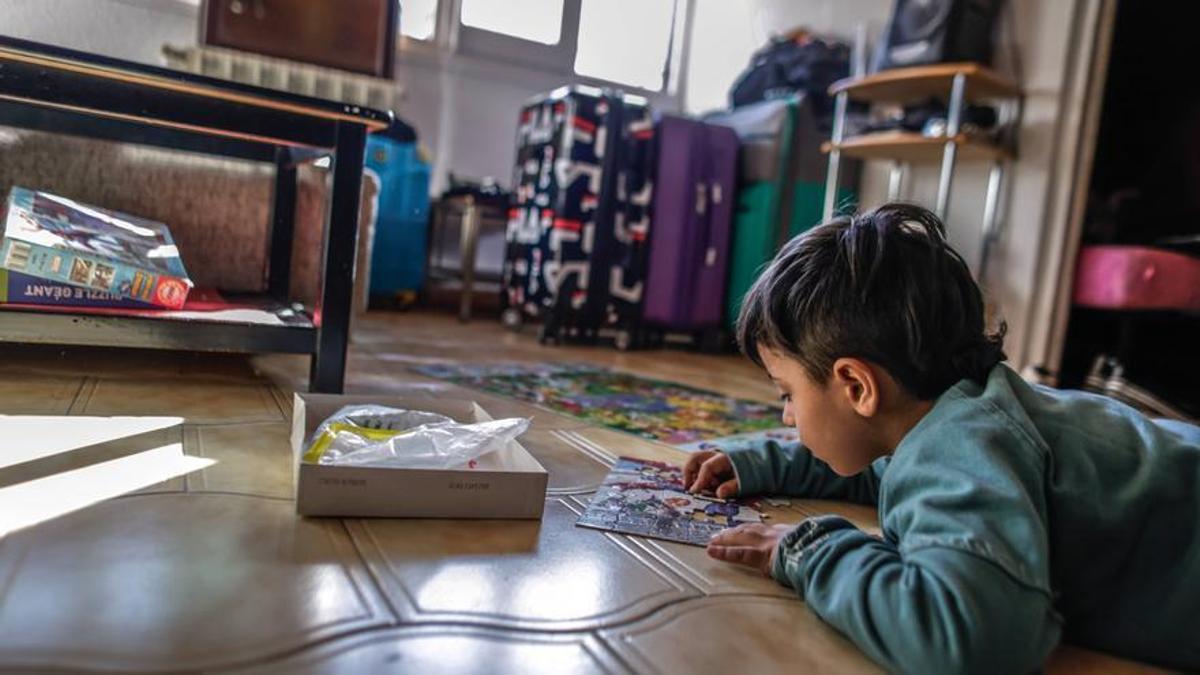 Jacabo, un niño de seis años que no ha podido ir al médico por no estar empadronado en Ripoll, juega en el suelo.