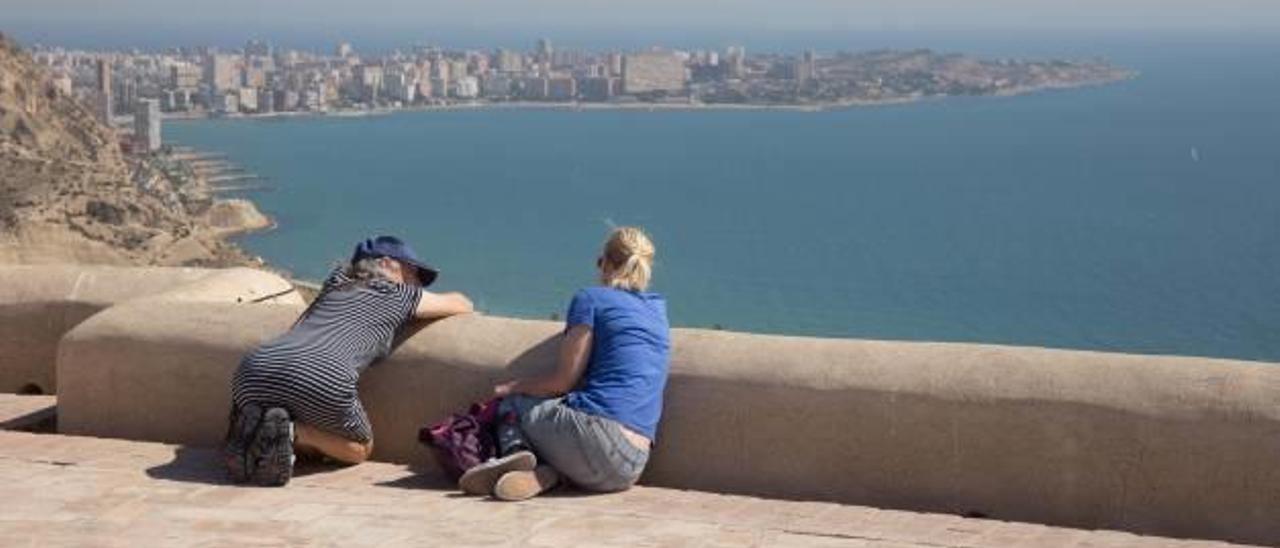 Una pareja de turistas contempla la bahía de la Albufereta desde un mirador del Castillo de Santa Bárbara.