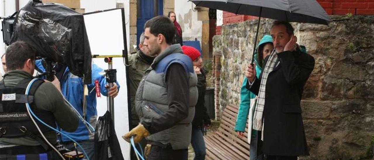 El actor Gonzalo de Castro, bajo un paraguas, en la plaza de Lastres durante el rodaje de &quot;Doctor Mateo&quot;.