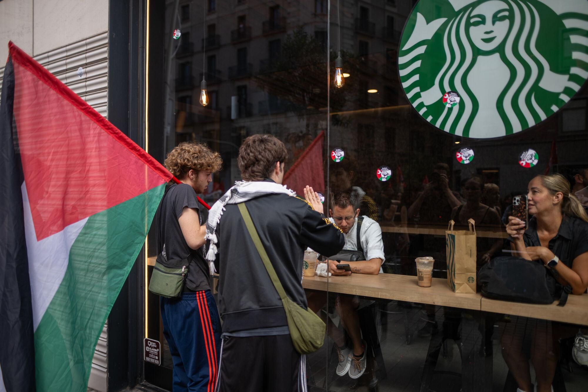 Un chico pega pegatinas de la bandera palestina en un escaparate durante una manifestación del sindicato de Estudiantes en apoyo al pueblo palestino, a 2 de octubre de 2025, en Barcelona, Cataluña (España). La protesta está convocada como parte de la huelga general estudiantil en apoyo al pueblo palestino, en protesta contra la intervención militar de Israel y la crisis humanitaria en Gaza. 02 OCTUBRE 2025;MANIFESTACIÓN;CONCENTRACIÓN;ESTUDIANTES;PALESTINA;PROPALESTINA; Lorena Sopêna / Europa Press 02/10/2025. Lorena Sopêna;