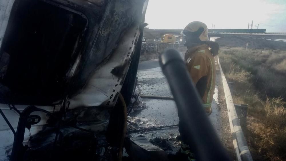 Los bomberos del Parque Comarcal de Elda refrigeran el tráiler que ha volcado y posteriormente se ha incendiado