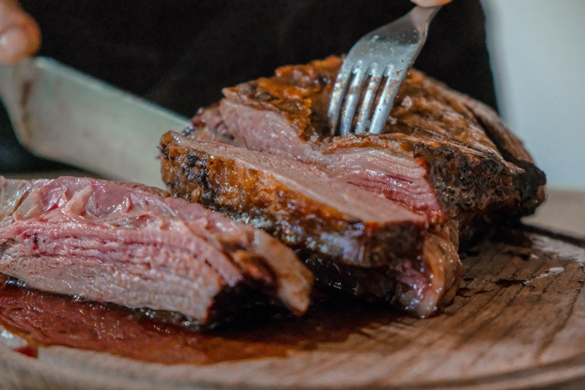 Una persona corta un trozo de carne.