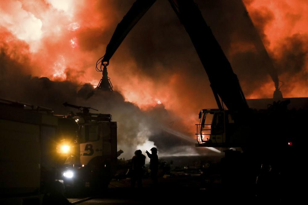 Labores de extinción del incendio de un desguace en Gijón