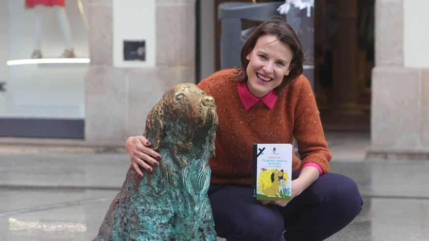 Marta Villar amosa o seu novo libro na praza de Lugo, coa estatua do can Ney.   | // IAGO LÓPEZ