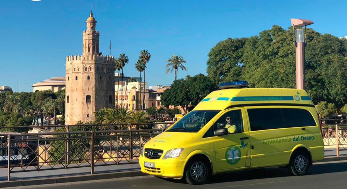 La ambulancia del deseo de Sevilla pasando por la Torre del Oro de la capital hispalense.