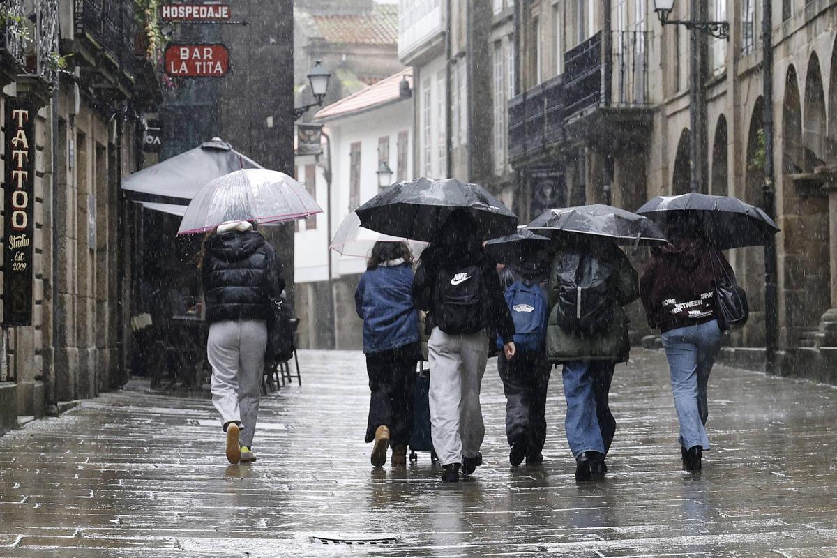 Un grupo de estudiantes se protegen con sus paraguas en un día de lluvia en Santiago