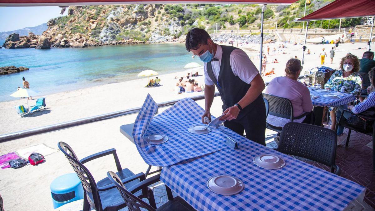 Un camarero trabajando en el restaurante junto a Cala Cortina en Cartagena, este verano. | IVÁN URQUÍZAR