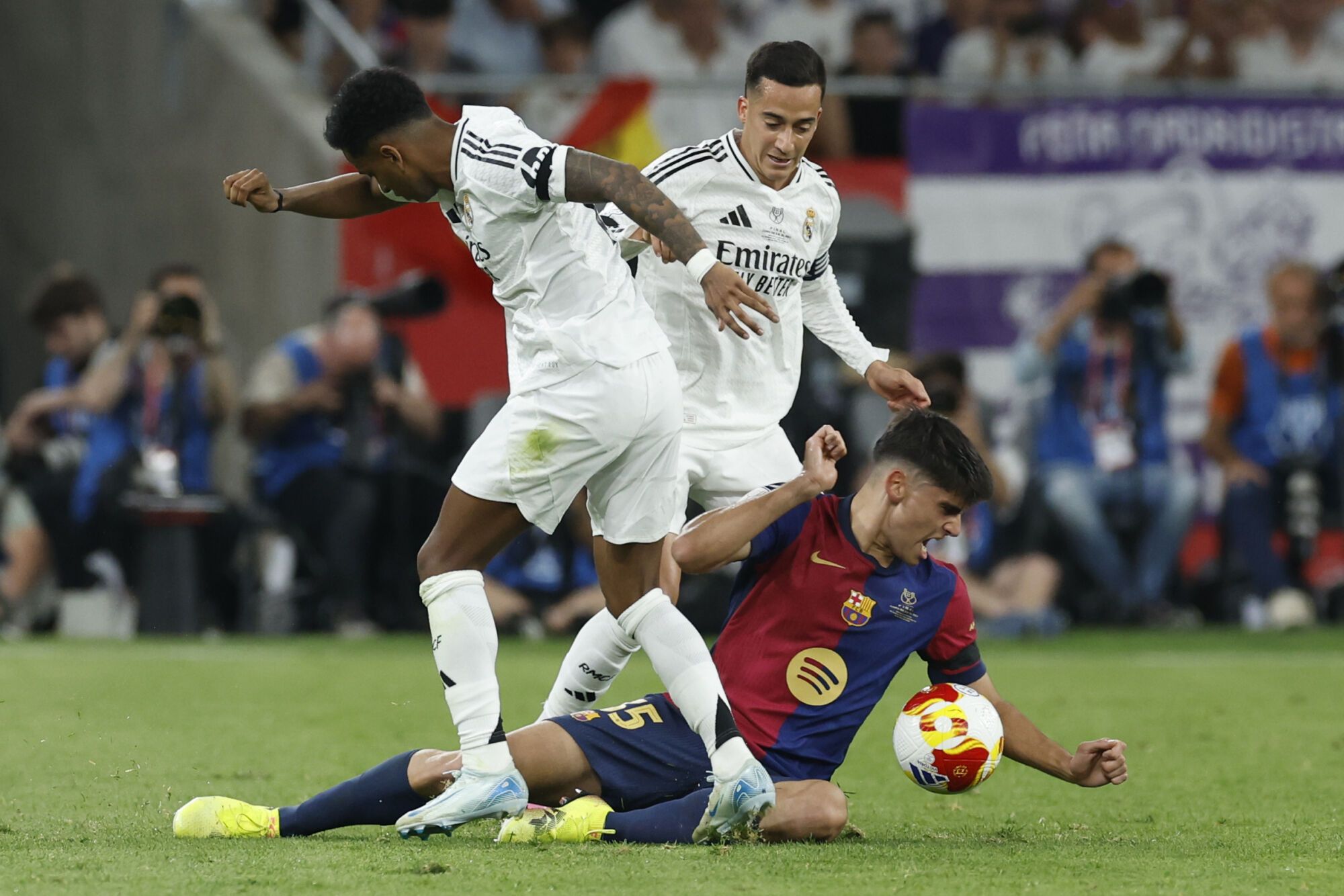 SEVILLA, 26/04/2025.- El defensa del Real Madrid Lucas Vázquez (detrás) y su compañero Rodrygo Goes pelean un balón con el defensa del Barcelona Gerard Martín (d) durante la final de la Copa del Rey que disputan Real Madrid y FC Barcelona hoy sábado en el estadio de La Cartuja, en Sevilla. EFE/Julio Muñoz