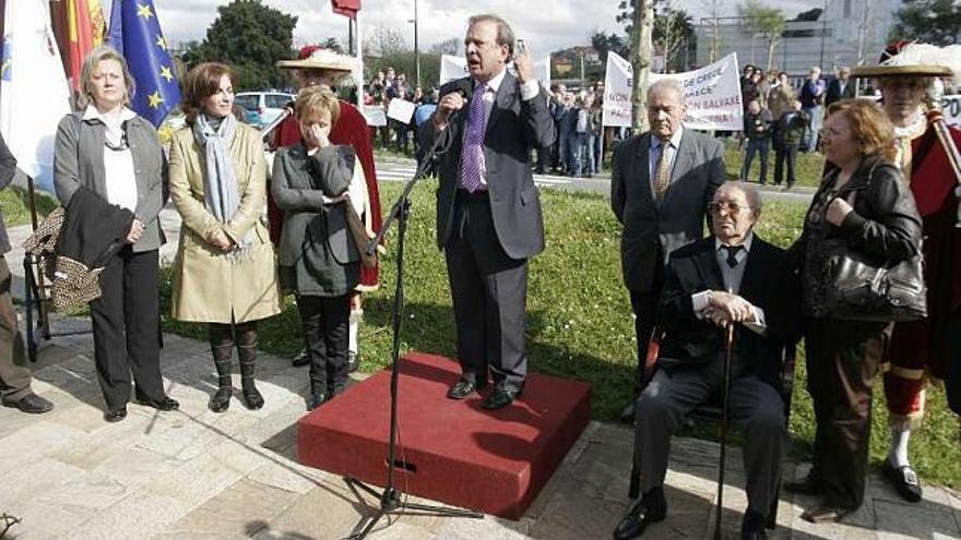El concejal González-Garcés pronuncia el discurso con las pancartas de los vecinos al fondo. / eduardo vicente