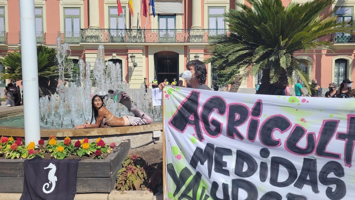 Una joven ataviada con un disfraz de sirena se moja por el Mar Menor en la céntrica plaza de La Glorieta de Murcia.