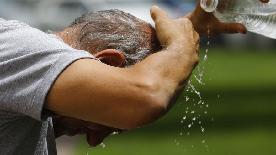 Un hombre se refresca con una botella de agua.