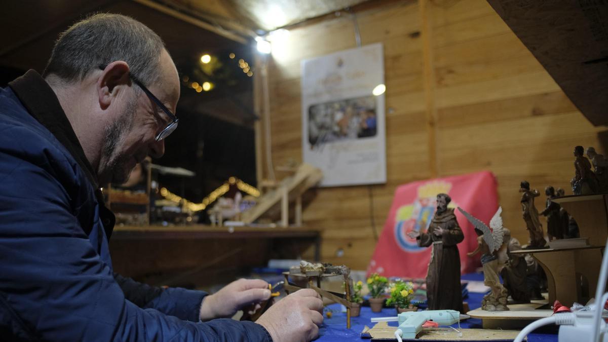 Un miembro de la Asociación Belenista de Cartagena elabora una figura en 2025 en el mercadillo de Juan XXIII.