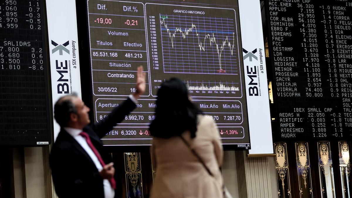 Dos personas frente a un panel de valores del Ibex 25 en el Palacio de la Bolsa