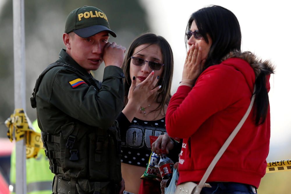 A police officer and two women wipe their tears ...