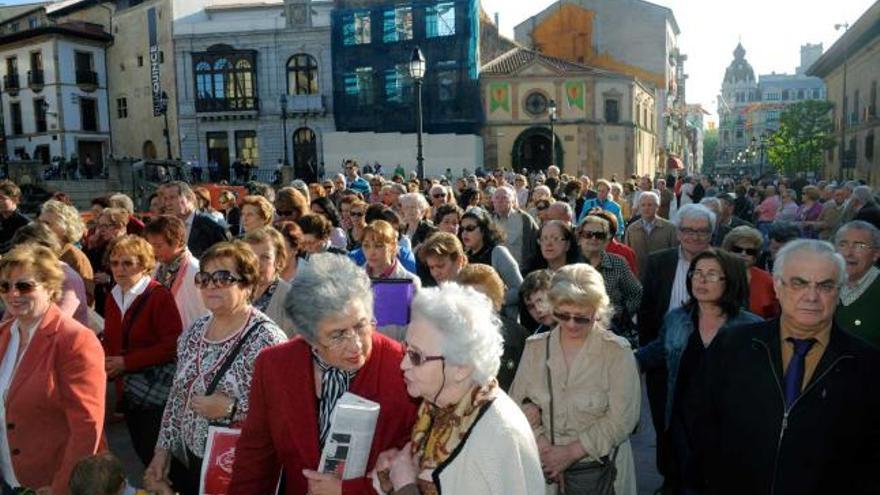 Sobre estas líneas, la Virgen de la Esperanza se encara con la torre de la Catedral. Debajo, los devotos, en procesión, y a la derecha, Mercedes González empuja la silla con su hijo, Jaime Barrera, uno de los cofrades más pequeños. | nacho orejas