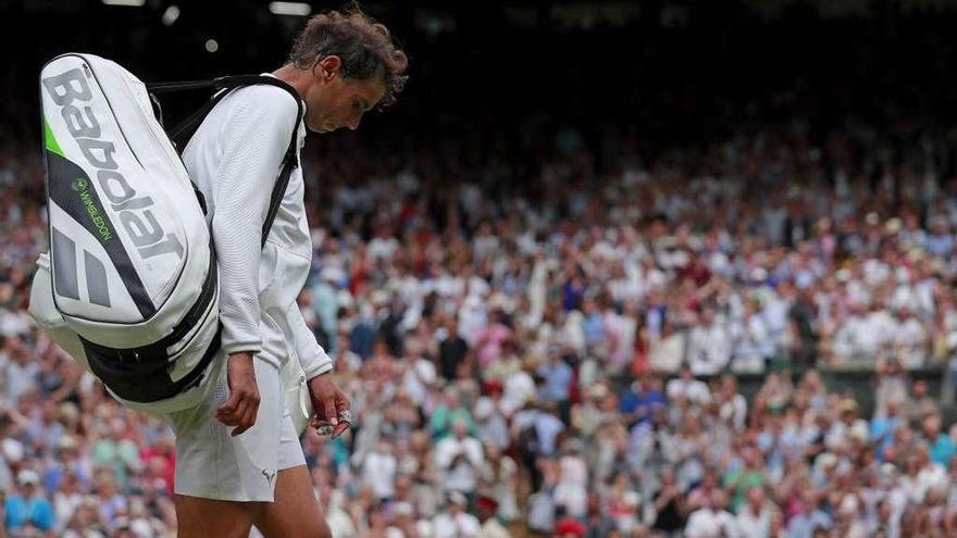 Nadal abandona con la cabeza baja la pista central de Wimbledon. // Efe