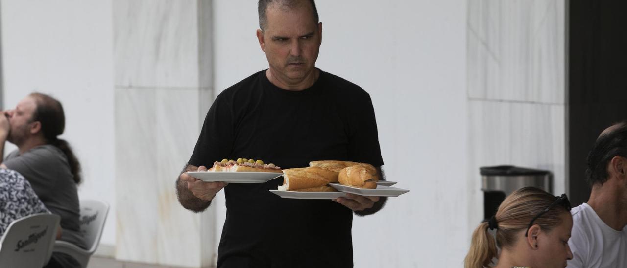 Un camarero llevando los bocatas del almuerzo en un bar de València.