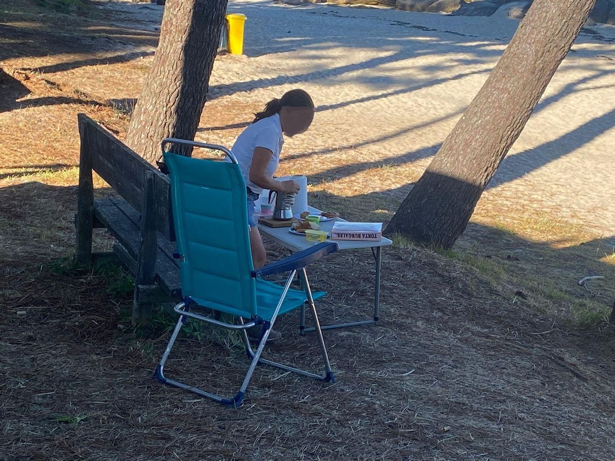 Una autocaravanista poniendo la mesa a pie de playa.