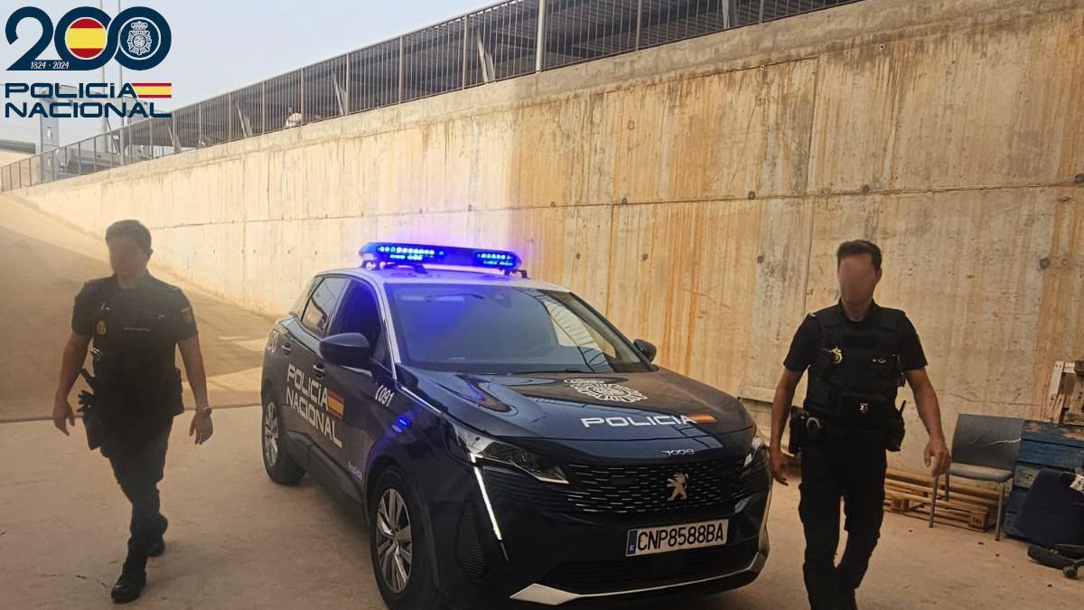 Dos agentes de la Policía Nacional junto a su coche patrulla.