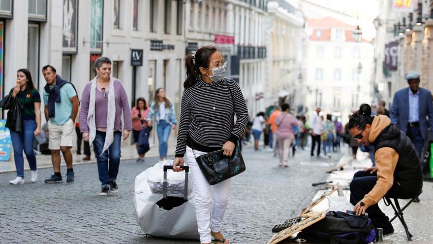 Una turista camina hoy con mascarilla por las calles de Lisboa.