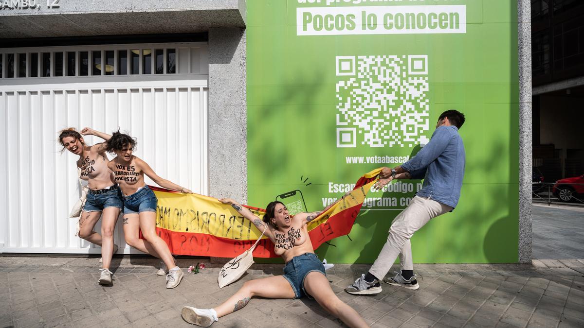 Una persona trata de impedir una protesta del colectivo activista Femen frente a la sede nacional de Vox.