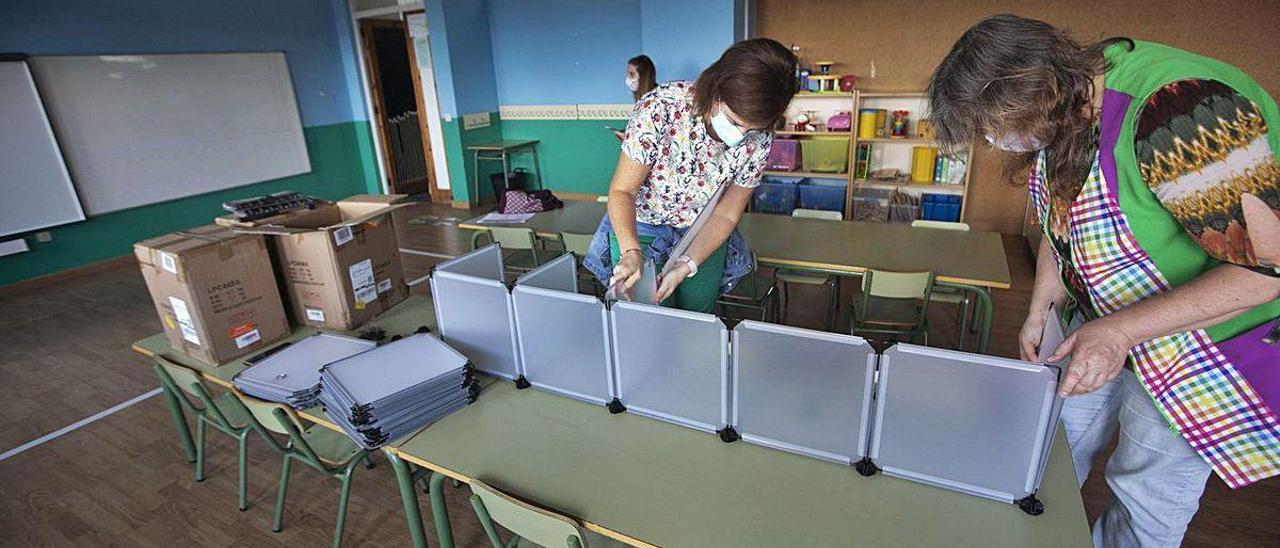 Las profesoras Paloma Armada y Cecilia Vega, montando ayer en un aula de 3 años del colegio Poeta Antón de Candás unas taquillas individuales para que los niños depositen su material escolar; al fondo, Laura Hevia.