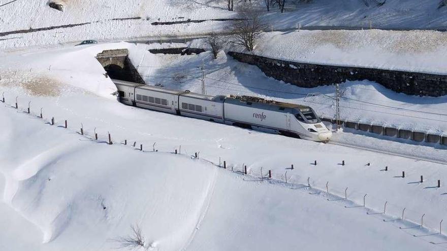 Un Alvia circula entre la nieve por el trazado ferroviario de Pajares.