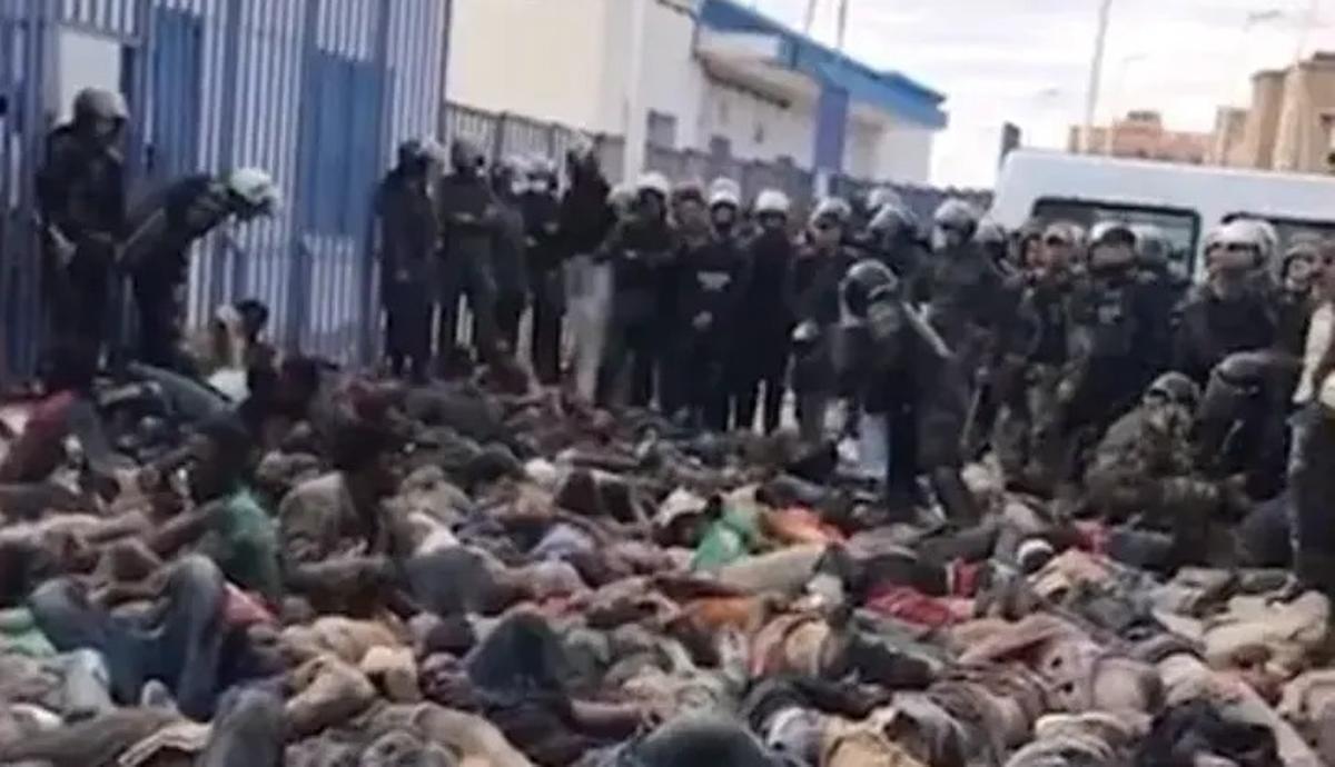 Migrantes subsaharianos yacen en el suelo del patio del puesto fronterizo del Barrio Chino de Nador entre gendarmes marroquís.