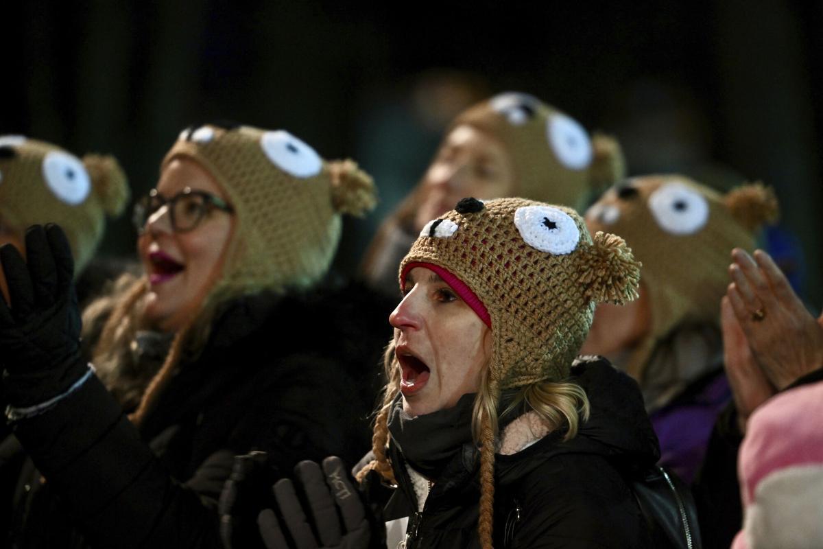 FILE - Ashley Johnson of Dallas watches entertainment while waiting for Punxsutawney Phil, the weather prognosticating groundhog, to come out and make his prediction during the 136th celebration of Groundhog Day on Gobbler's Knob in Punxsutawney, Pa., Wednesday, Feb. 2, 2022. (AP Photo/Barry Reeger, File). FILE