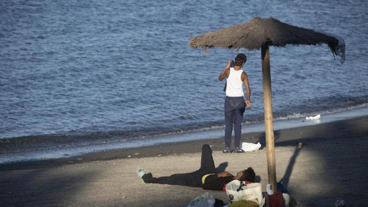 Dos migrantes, en la playa de El Trampolín de Ceuta.