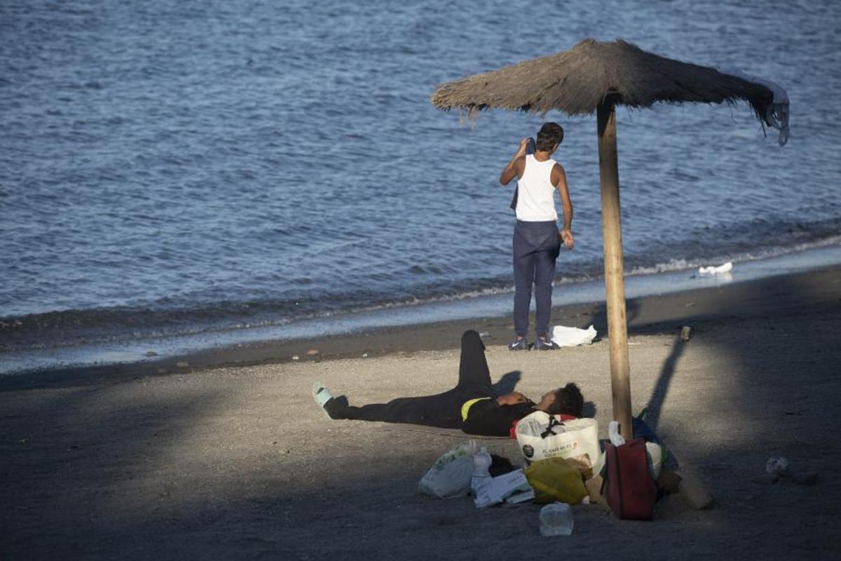 Dos migrantes, en la playa de El Trampolín de Ceuta.
